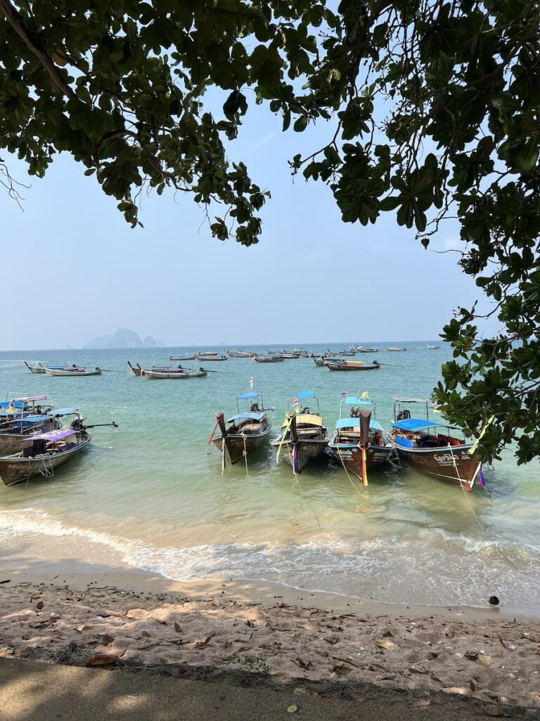 Boats docked on a budget beach near the ocean in Thailand.